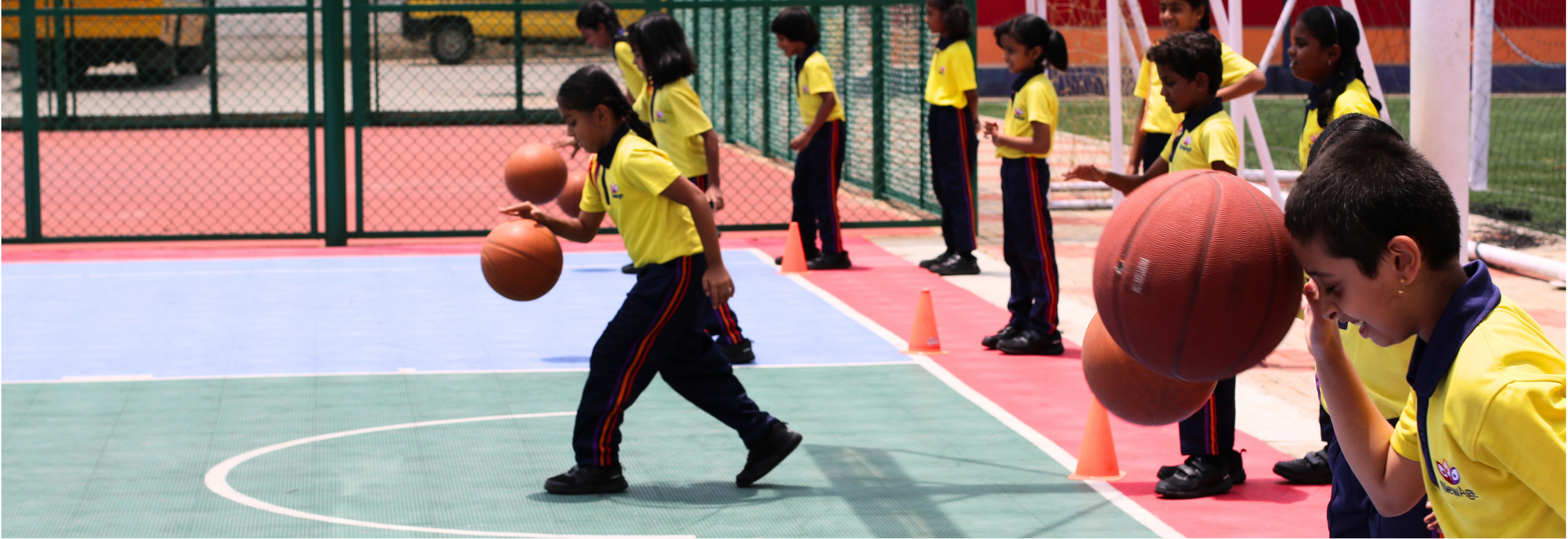 Students at NewAge World School engaged in a basketball dribbling drill on the outdoor court, enhancing their coordination and sports skills.